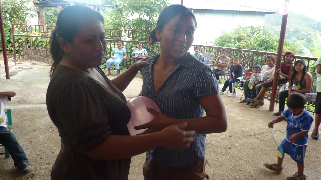 Madres participando concurso de reventar globos en una celebración del Centro