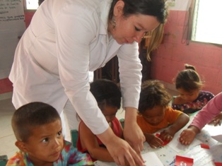 Una de las doctoras de pasantía auxiliando a un niño con los ejercicios manuales