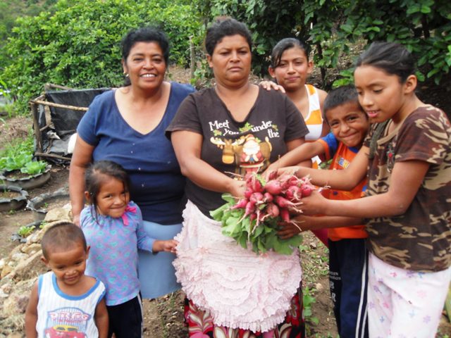 Madres y niñas-os mostrando producción del rábanos del huerto